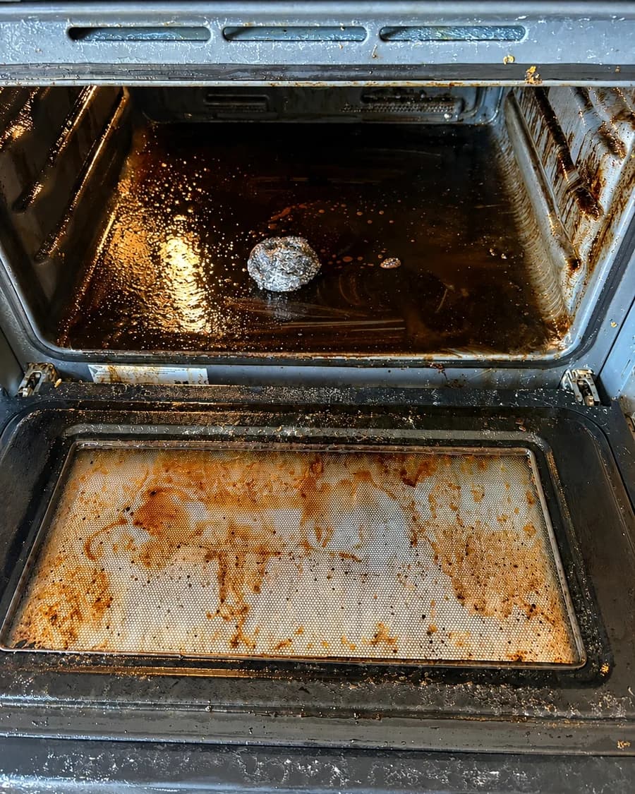 Ovenbinnenkant met ingebrand vet en aangekoekte resten voor de reiniging
